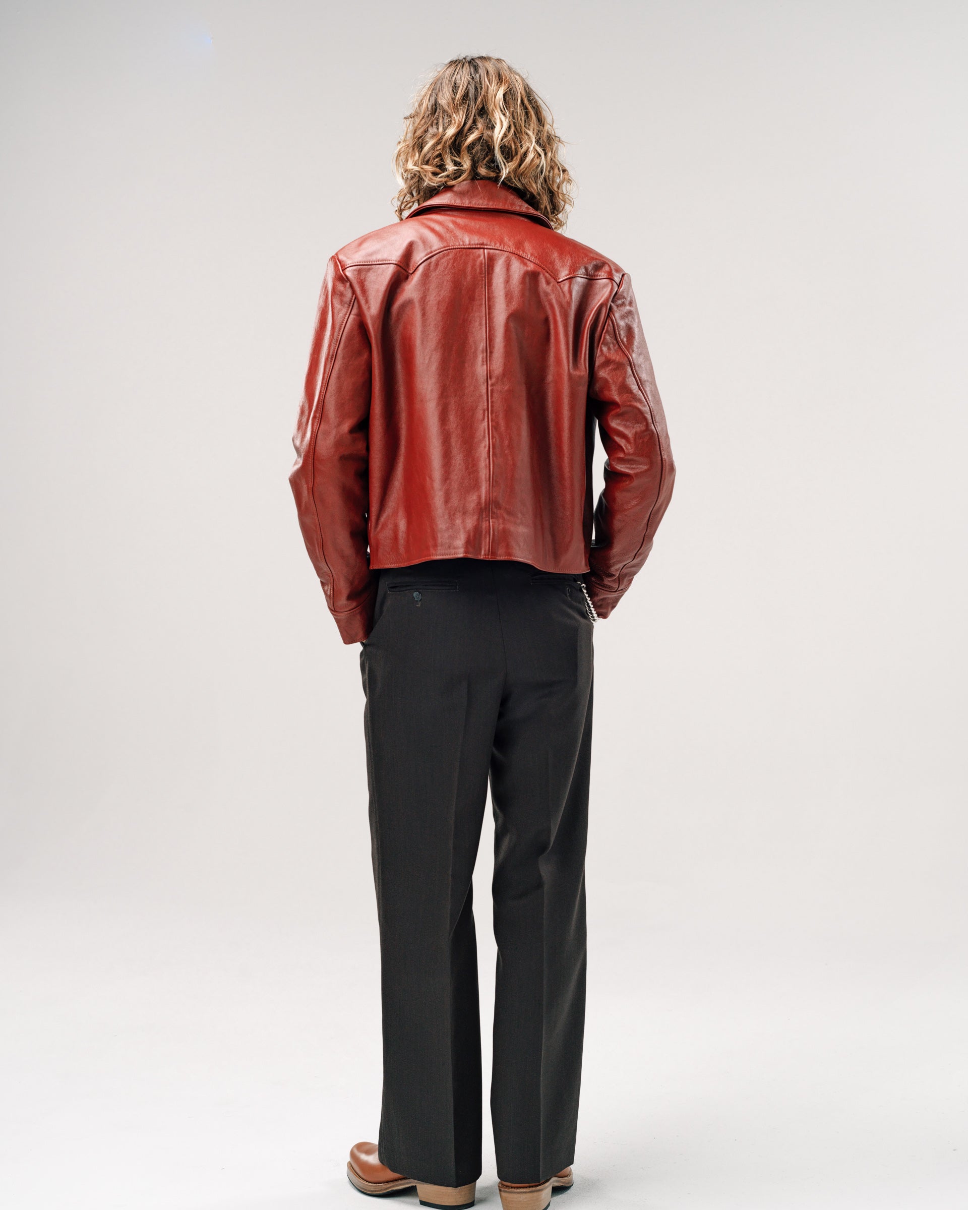 Person wearing a red leather jacket and black pants on a white background
