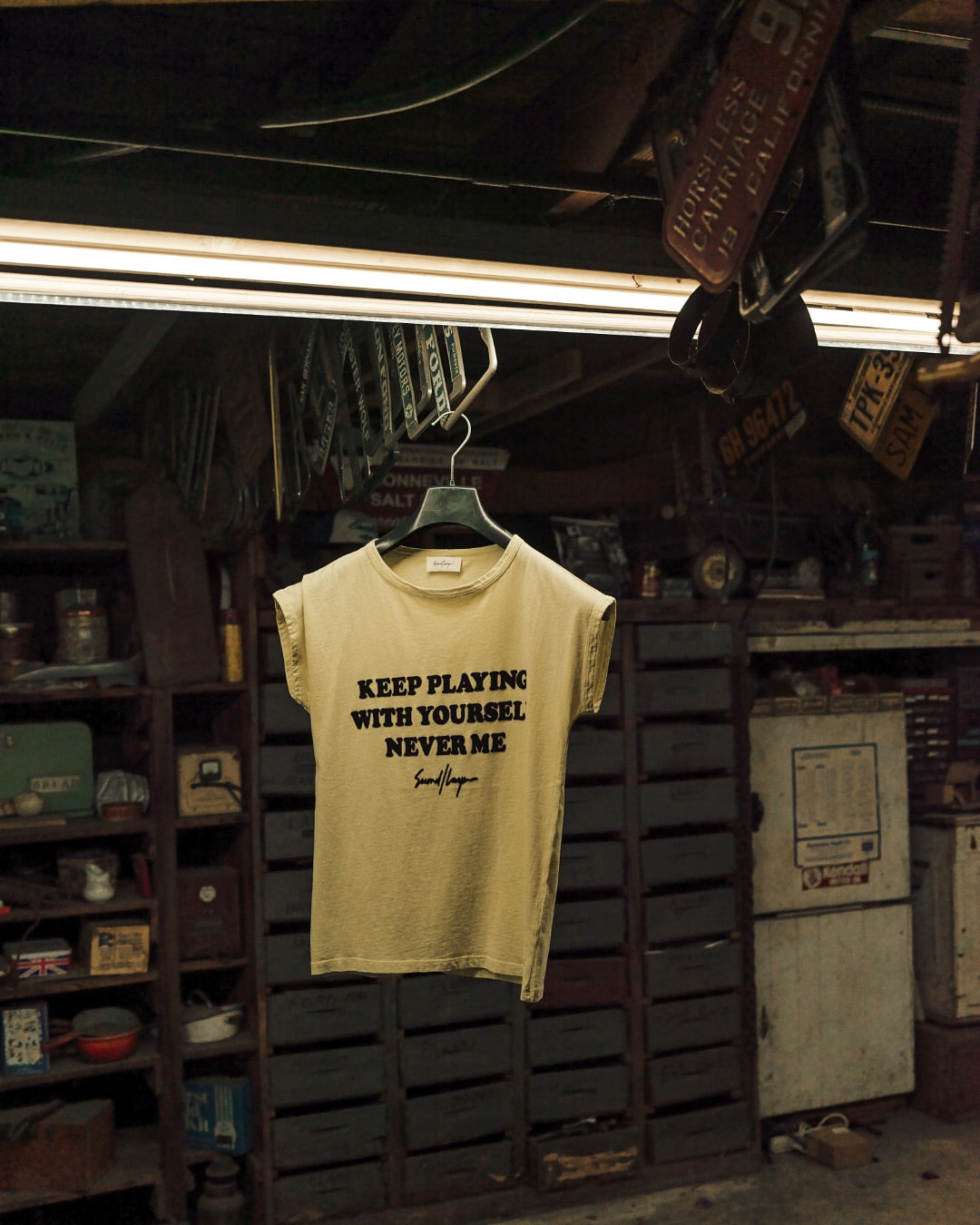 Yellow t-shirt with text hanging in a workshop.
